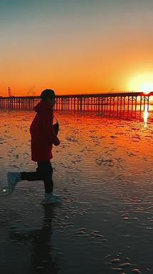 冬天日出在海滩上奔跑的少年